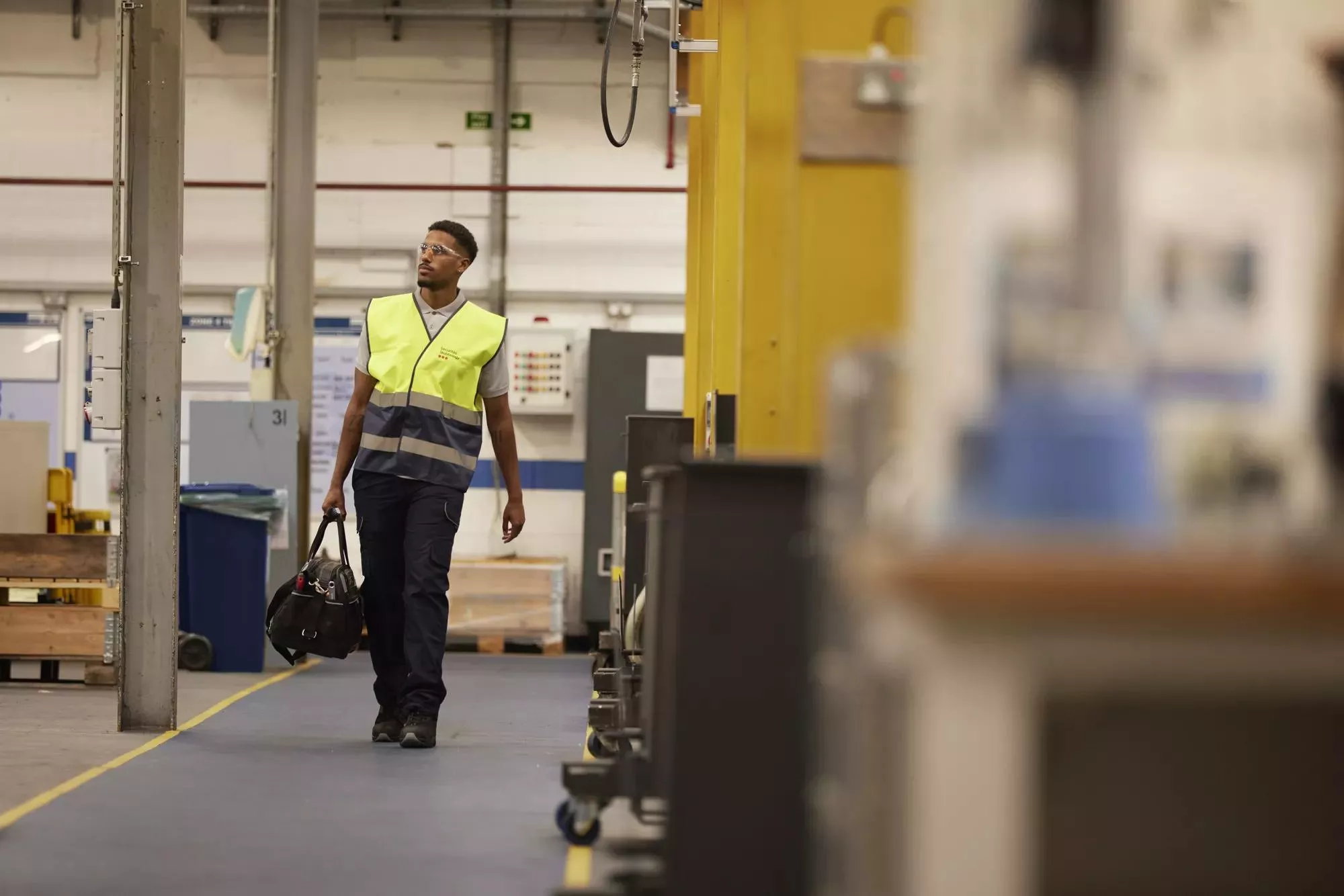 a technician wearing a safety vest walking through an industrial facility, representing Securitas Technology's commitment to on-site security service and maintenance