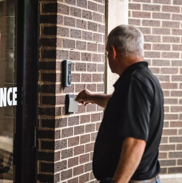 person swiping card reader on door using commercial smart lock access control credentials