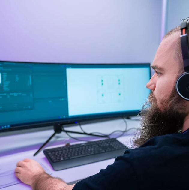 security monitoring professional sitting in front of a video surveillance monitoring system with multiple screens showing security camera feeds