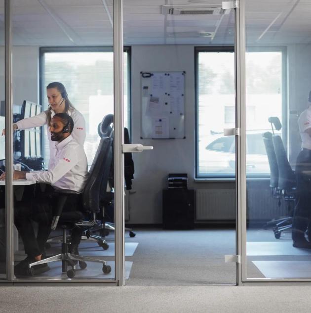  a professional security operator seated at a desk in a monitoring center, surrounded by multiple screens displaying live security camera feeds, system alerts, and analytics.