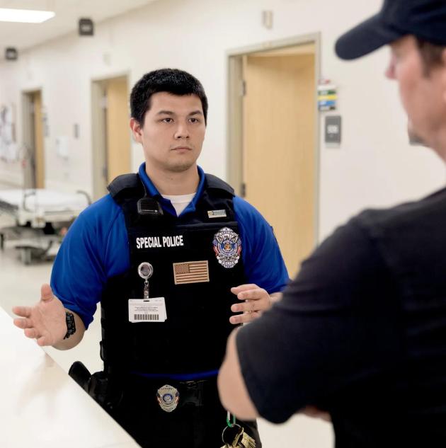 Security officer summoned by Staff Protection badge confronts disruptive hospital visitor. Securitas Healthcare.