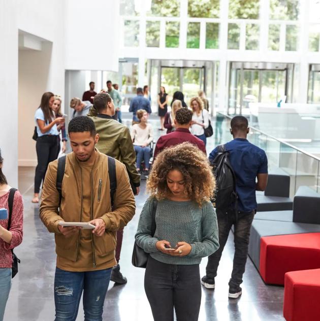 Students walk in university campus using tablets and phone