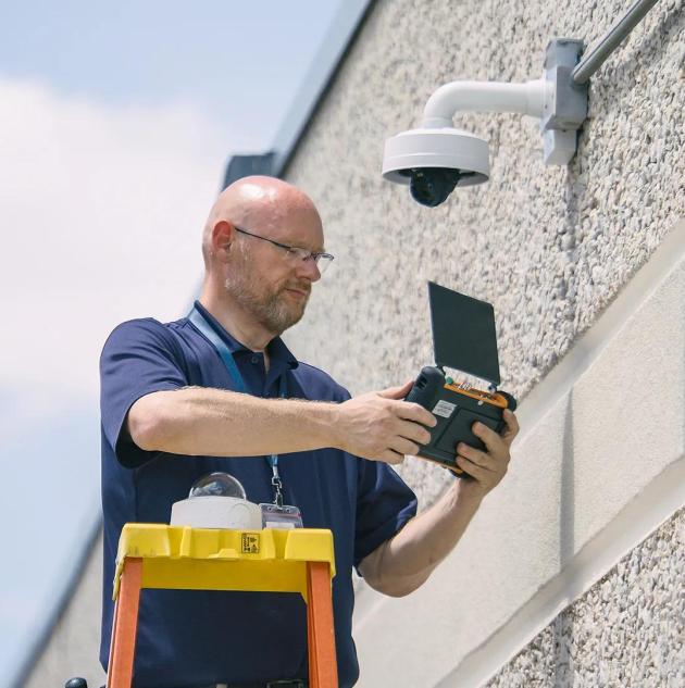 Securitas Technology technician mounting a dome camera outside a building to support reliable, cloud-based video surveillance