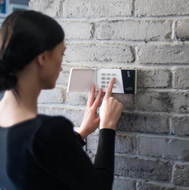 Young woman entering security pin on home alarm keypad. Home security system
