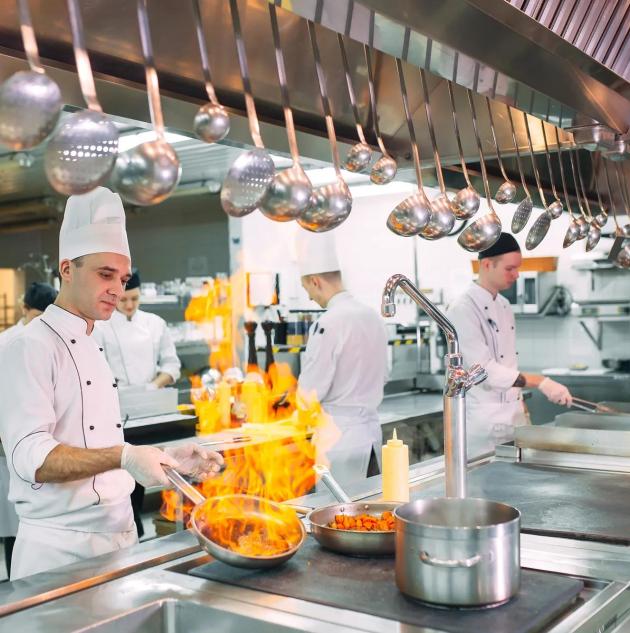Modern kitchen. Cooks prepare meals on the stove in the kitchen of the restaurant or hotel. The fire in the kitchen