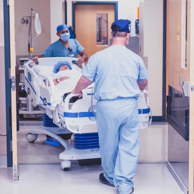 Medical personnel push gurney through automatic OR door