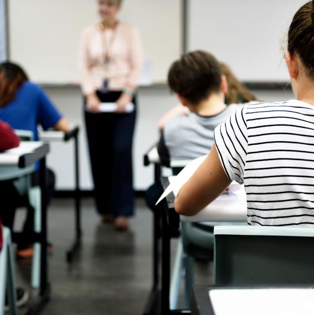 Backs of students sitting at classroom desks