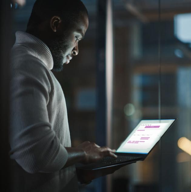 Man uses laptop in darkened room