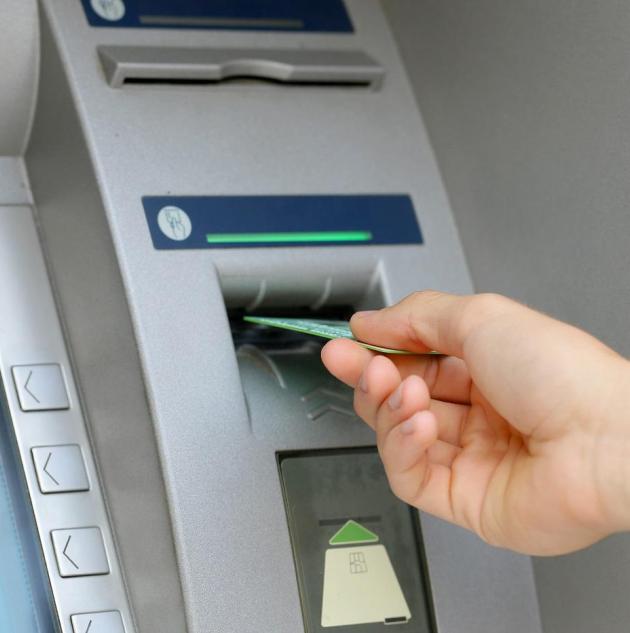 person inserting credit card into ATM machine