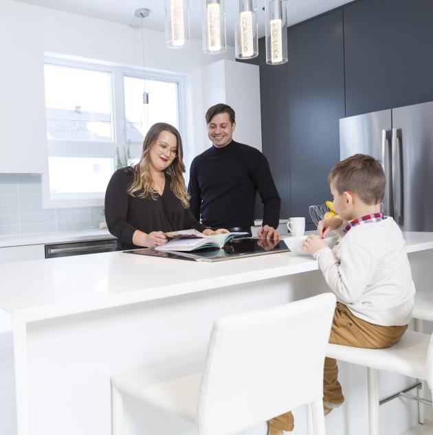 Family gathers at island bar in kitchen.