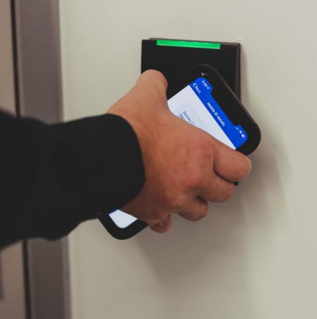 person holding up mobile phone to access control card reader