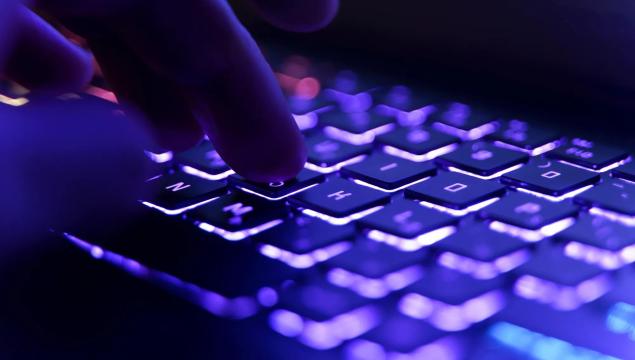 Working on a neon computer keyboard with colored backlighting. Computer video games, hacking, technology, internet concept. Selected focus. High quality photo