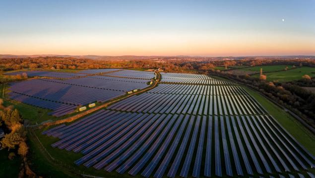 Aerial drone view of solar panels at a solar energy generation farm at Sunset in South Wales, UK