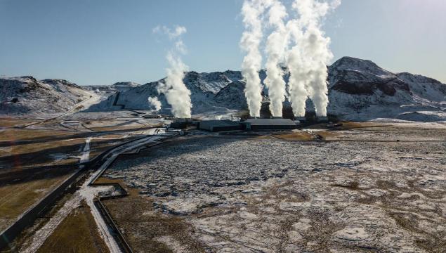 White steam billows from the geothermal power plant in Hellisheidi, Iceland, contrasting with the snowy peaks of Iceland's breathtaking winter scenery in this aerial