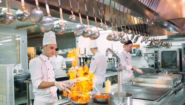 Modern kitchen. Cooks prepare meals on the stove in the kitchen of the restaurant or hotel. The fire in the kitchen
