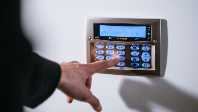 Person types code into access control security pad.