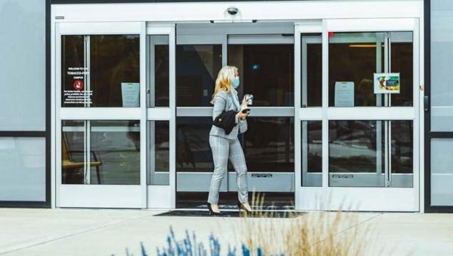 Woman entering building through external door using access control card
