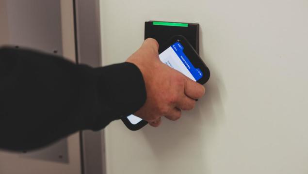 person holding up mobile phone to access control card reader 