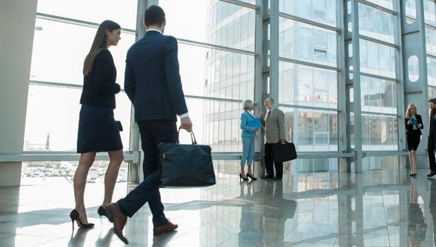 office workers walking through lobby of large office building with glass windows