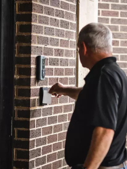 person swiping card reader on door access control panel 