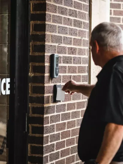 person swiping card reader on door using commercial smart lock access control credentials