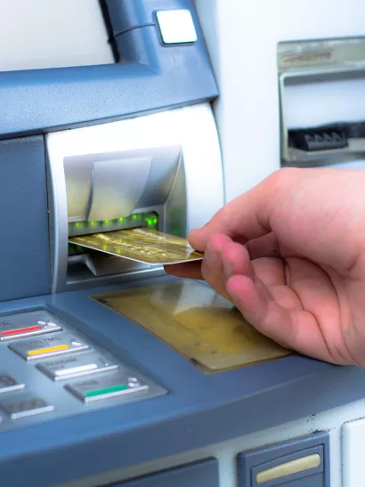 Hand inserts bank card into ATM slot.