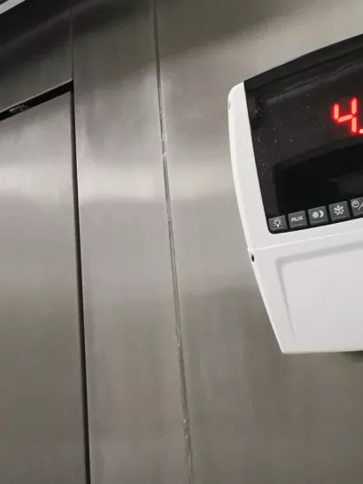 Smart thermostat on large, metal commercial freezer.