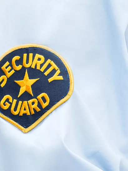 Security Guard patch on arm of white button-up shirt.