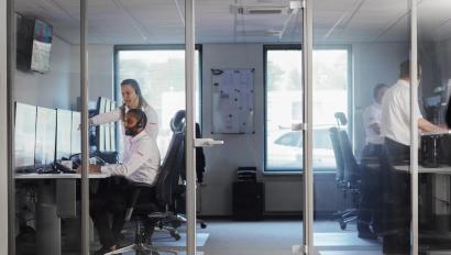  a professional security operator seated at a desk in a monitoring center, surrounded by multiple screens displaying live security camera feeds, system alerts, and analytics.
