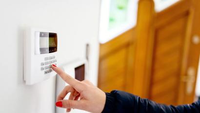 Young woman entering security code on home security alarm system keypad
