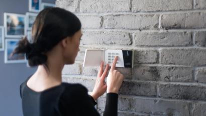 Young woman entering security pin on home alarm keypad. Home security system