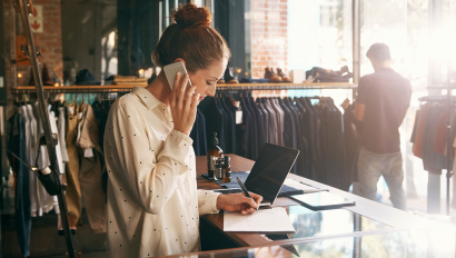 Woman on phone at counter of clothes store