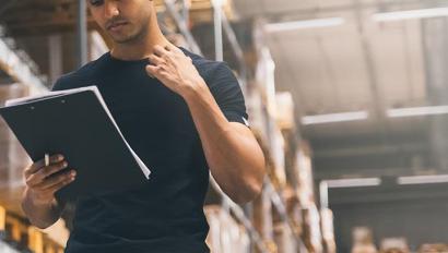 Man in hard hat with clipboard in warehouse
