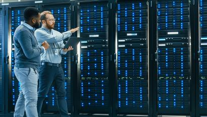 Two IT managers walk past row of servers