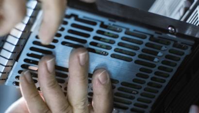 two hands insert a hard drive into a computer