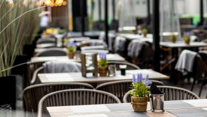 A photo of an empty restaurant with metal chairs and lavender on every table. 