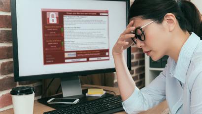 Frustrated woman holds forehead in front of computer