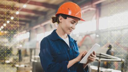 Woman in hardhat uses tablet.