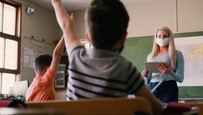 mask-wearing teacher in front of class