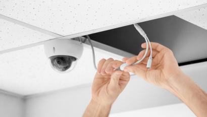 Technician installing CCTV camera on ceiling indoors