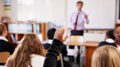 Female Student Raising Hand To Ask Question In Classroom