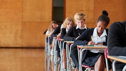 Teenage Students In Uniform Sitting Examination In School Hall